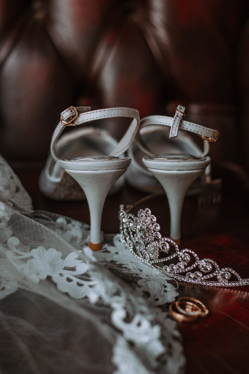 wedding rings with bridal accessories and shoes placed on couch