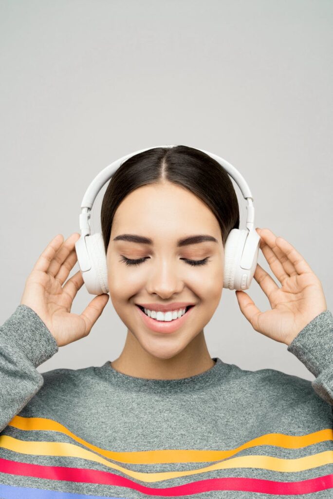 woman in gray sweater wearing white headphones