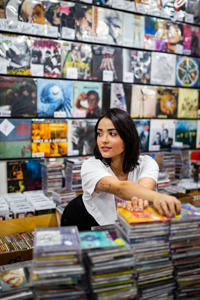 photo of woman standing near cds