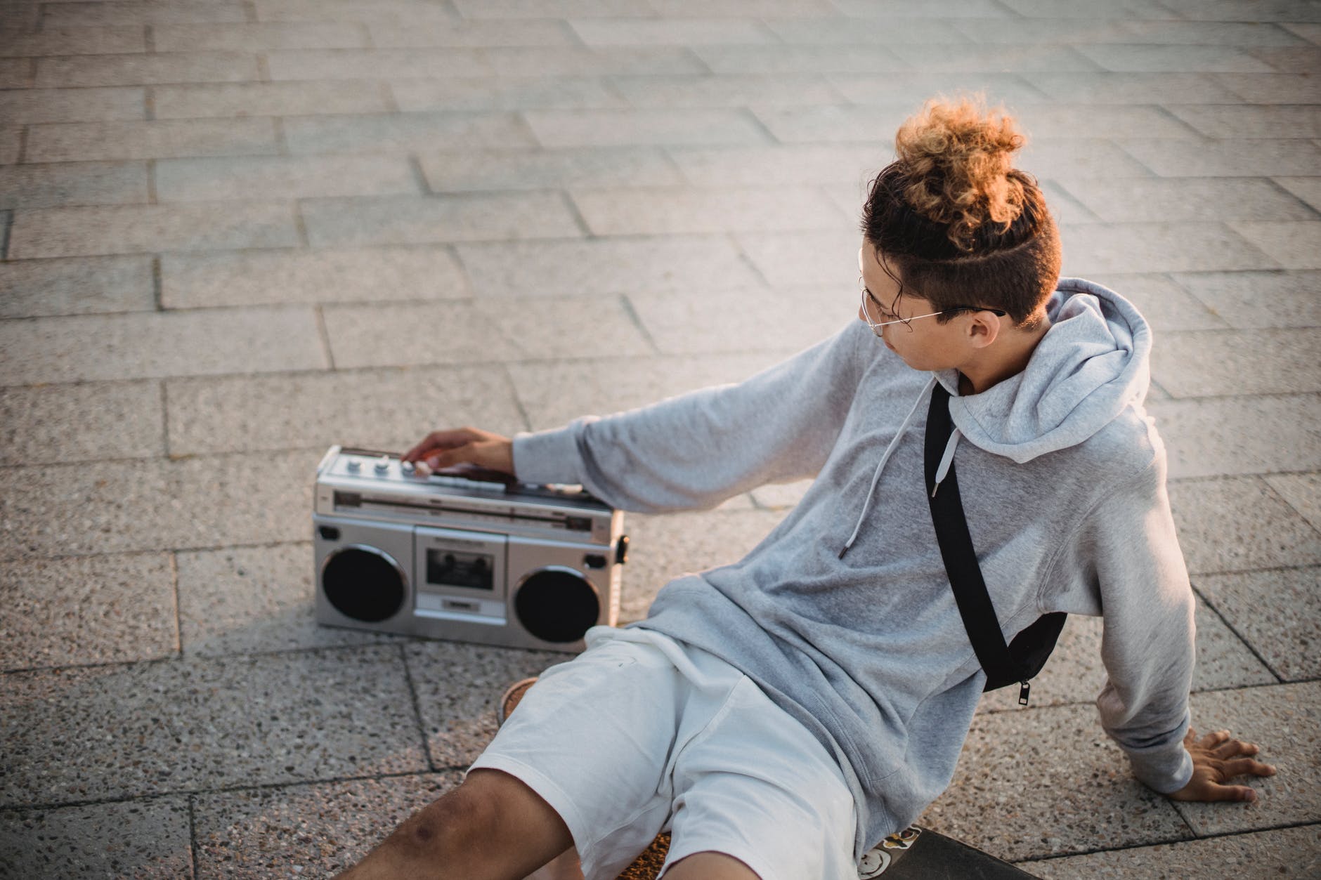 trendy young ethnic guy listening to music with boombox on street