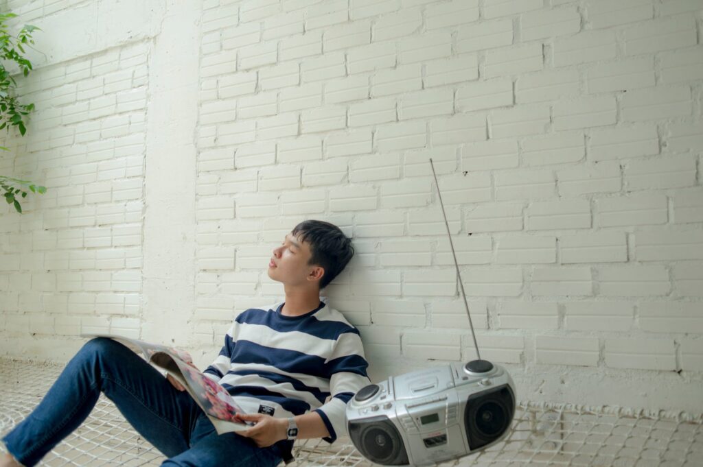 photo of man sitting near radio