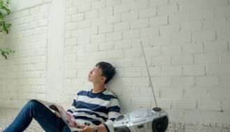 photo of man sitting near radio