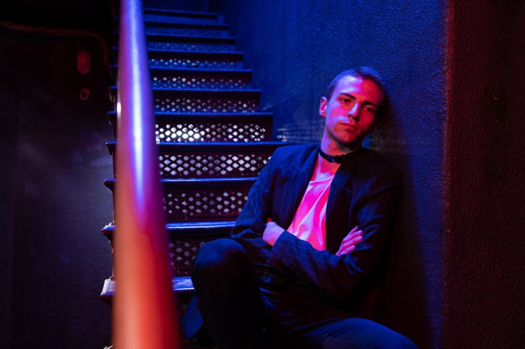 man in black suit jacket sitting on red chair