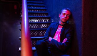 man in black suit jacket sitting on red chair