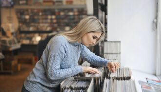 selective focus side view photo girl in gray sweater selecting vinyl records from a music store