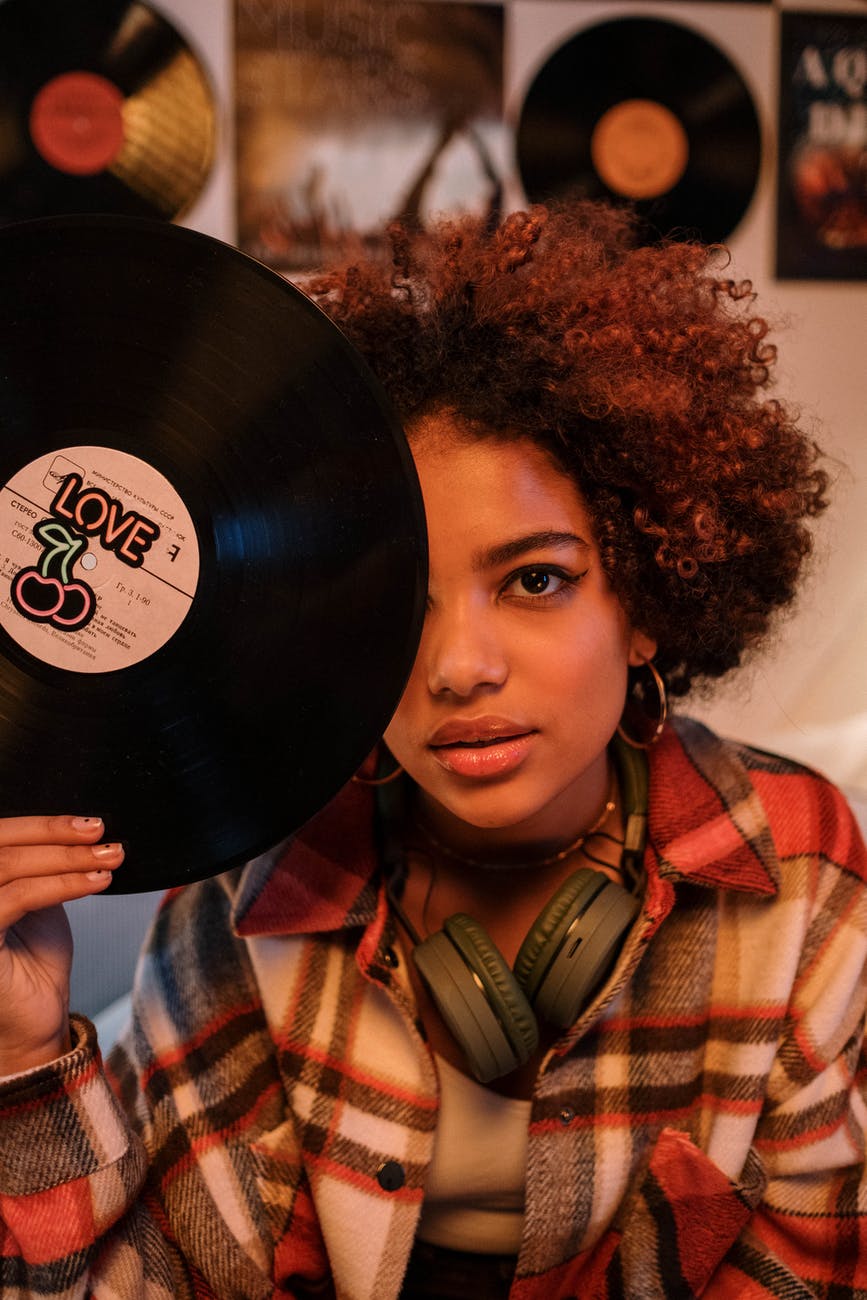 woman in plaid button up shirt holding vinyl record